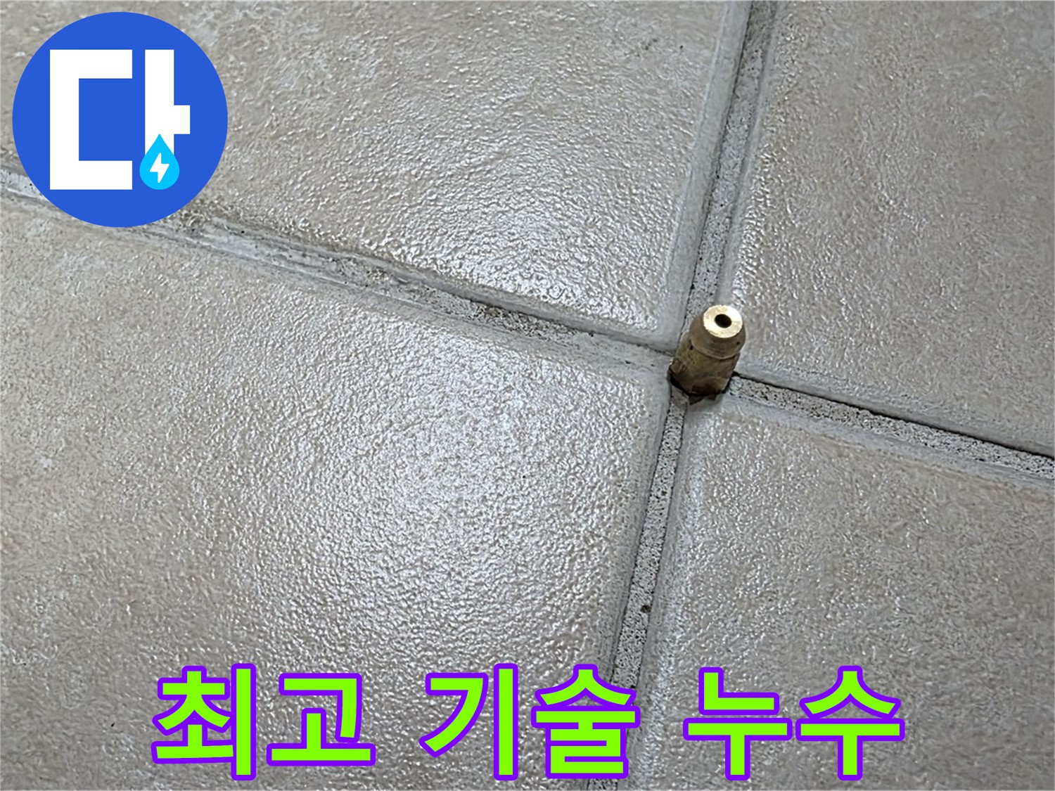 회색 타일 바닥 줄눈에 위치한 작은 황동 배관 소켓