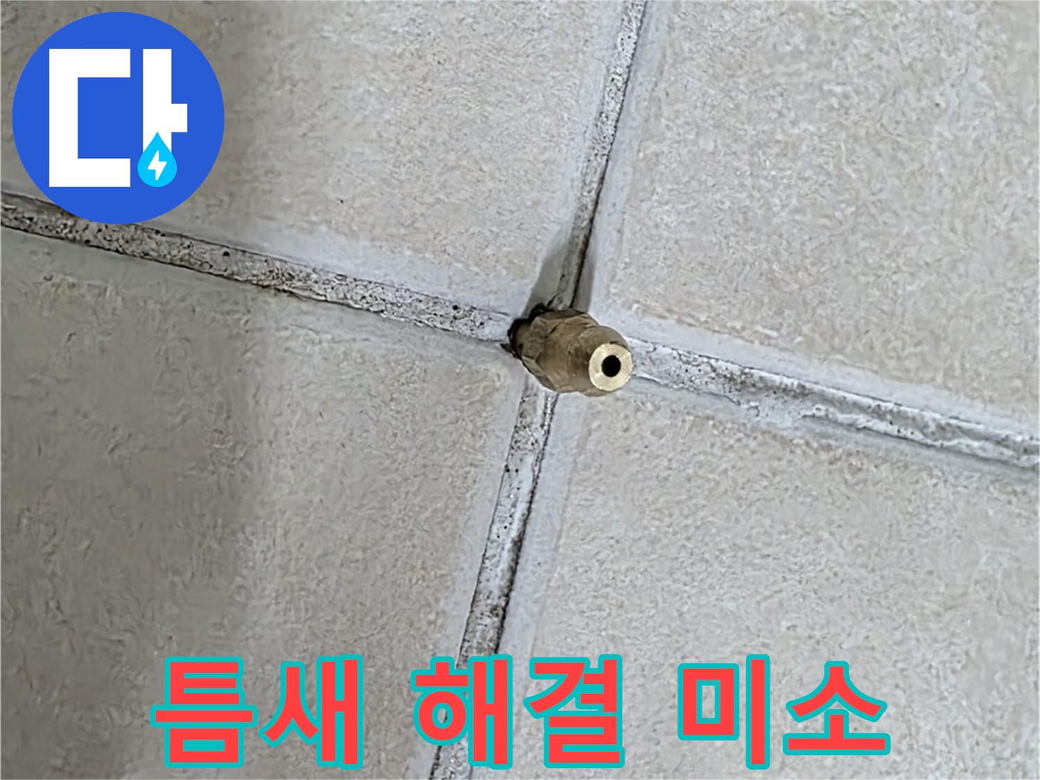 베이지색 타일 바닥 중앙에 위치한 금속 배관 부품입니다.