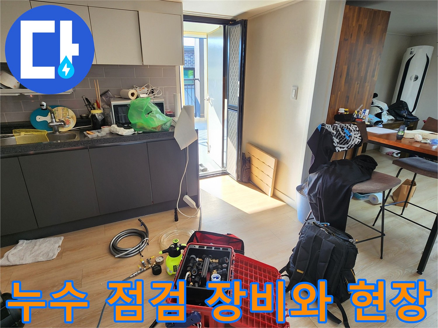 주방 바닥에 놓인 누수 탐지용 공압 테스트 장비와 각종 공구 세트