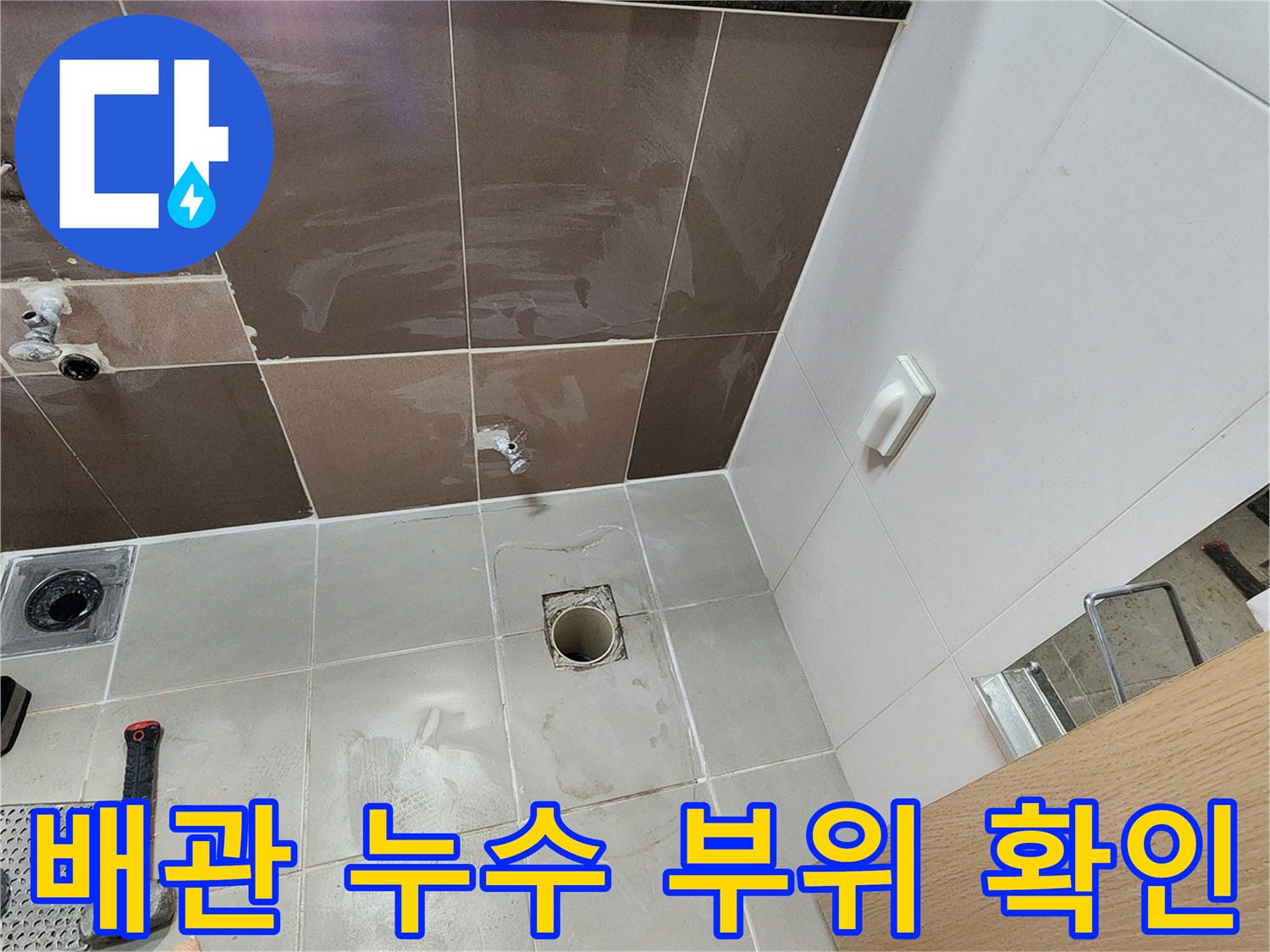 타일 아래 숨겨져 있던 수도 배관이 드러난 작업 모습입니다.