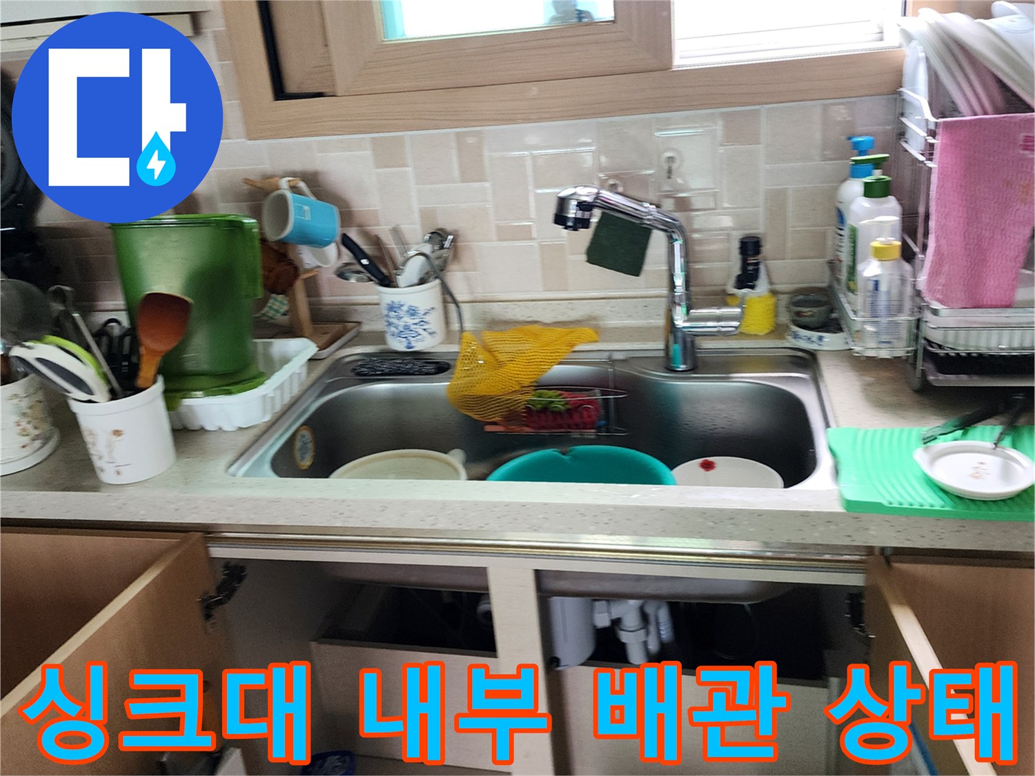 싱크대 하부장 내부에 노출된 배수 및 급수 배관의 모습