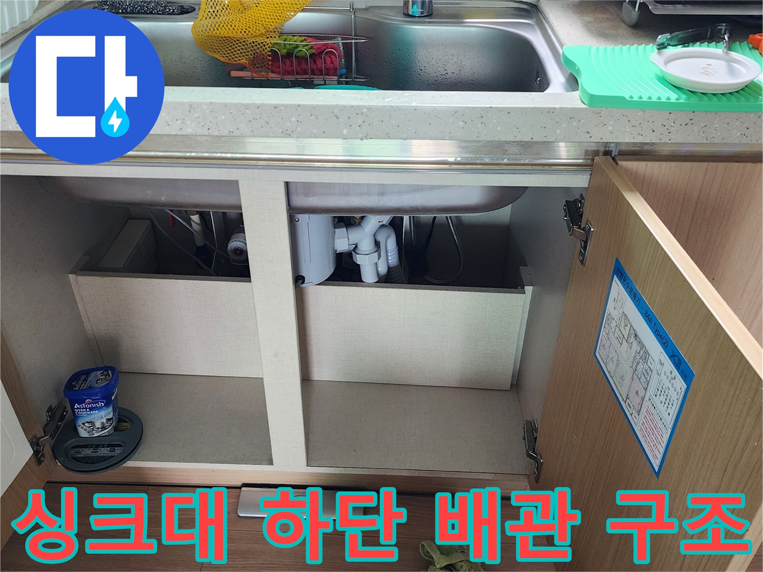 주방 싱크대 아래쪽의 배관 연결 부위와 하부장 내부 모습입니다.
