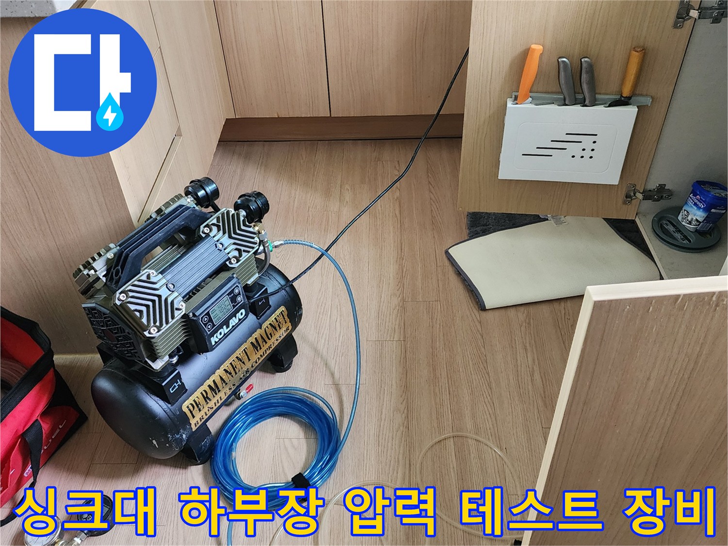 주방 싱크대 하부장에 설치된 공기압 테스트용 컴프레셔와 호스