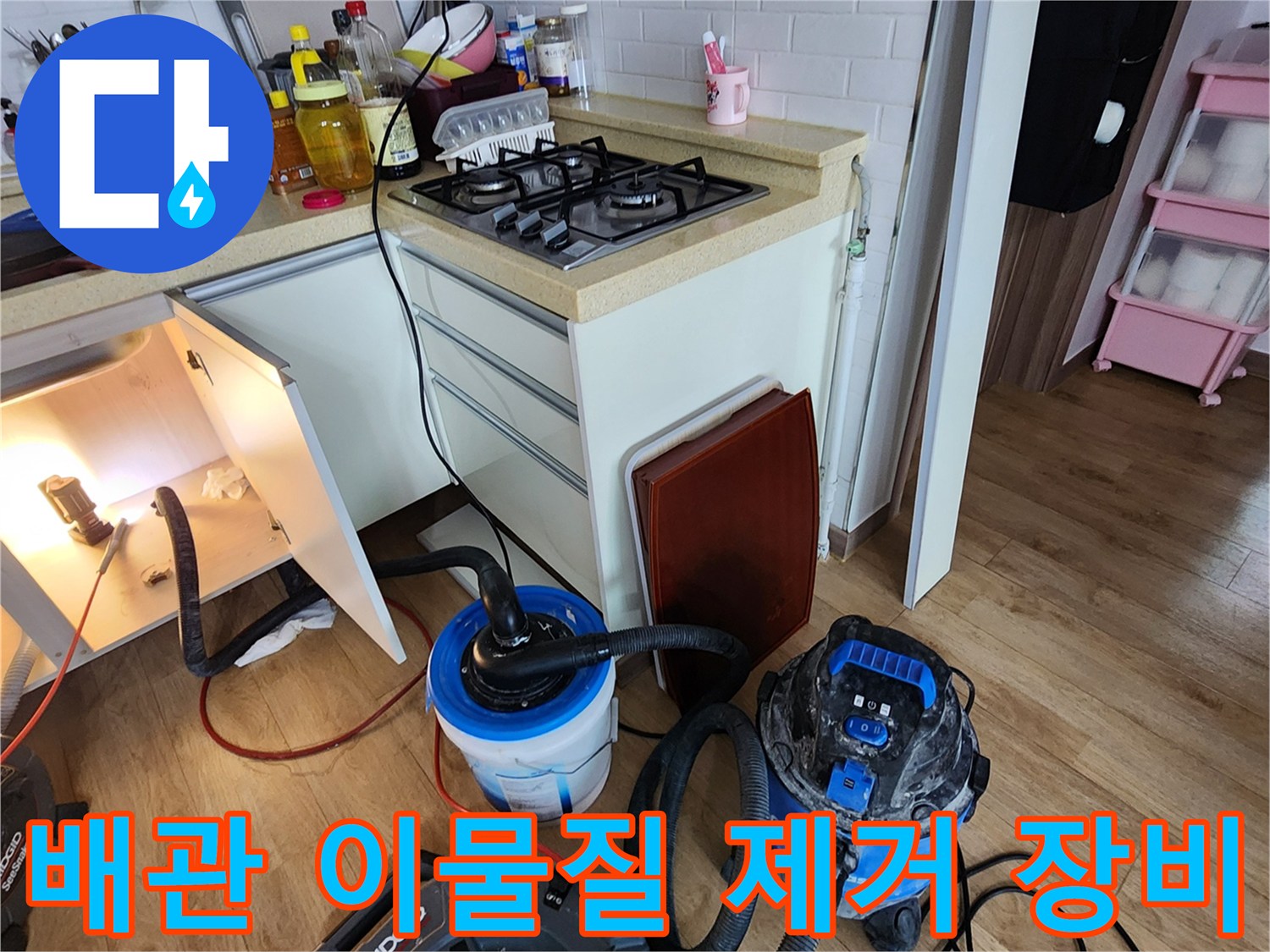 주방 하부장 내부-배관 청소를 위해 배치된 석션기와 흡입 호스 연결 상태