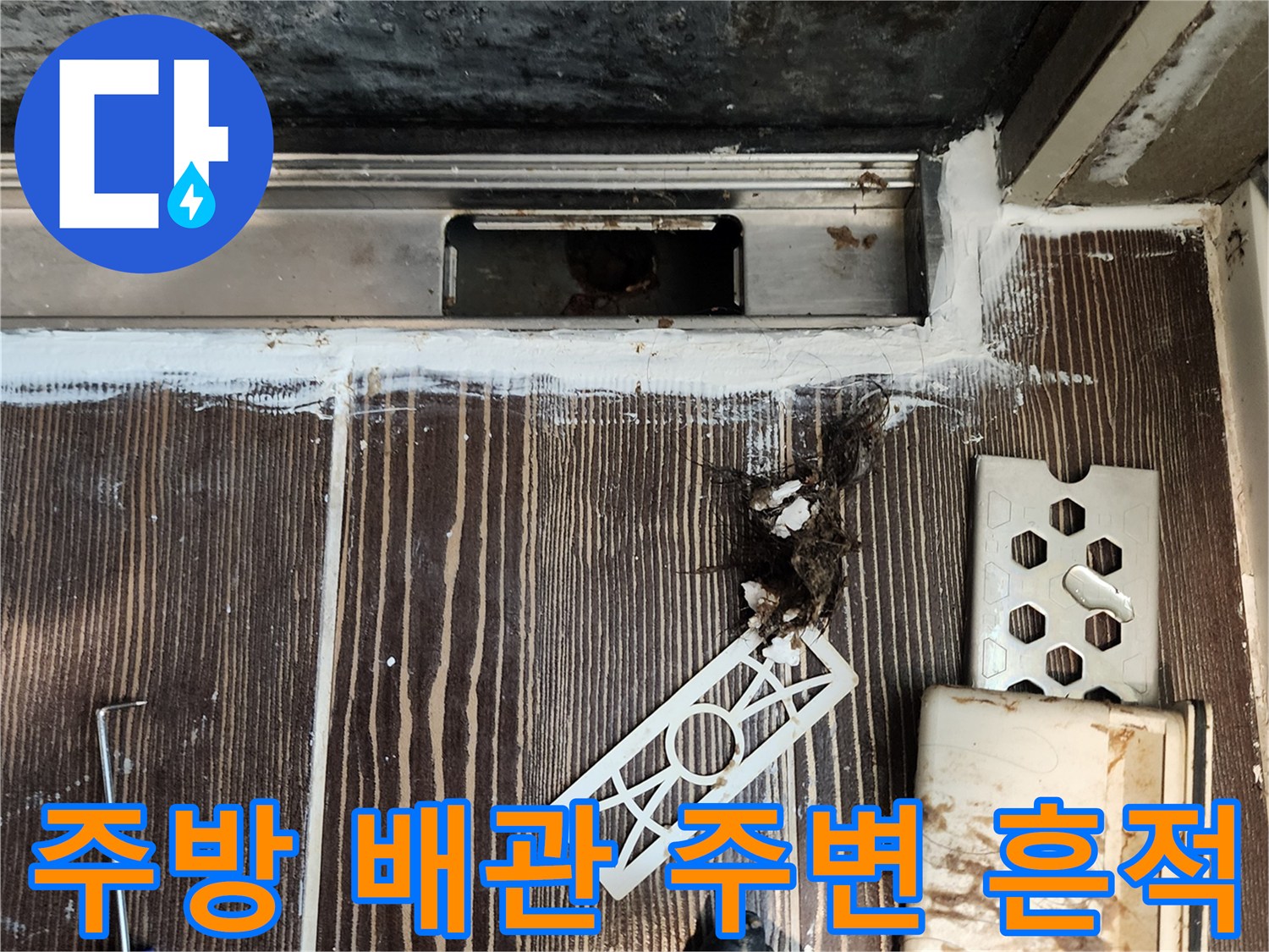 싱크대 아래 배관 주위의 하얀 백시멘트와 오염된 잔해들