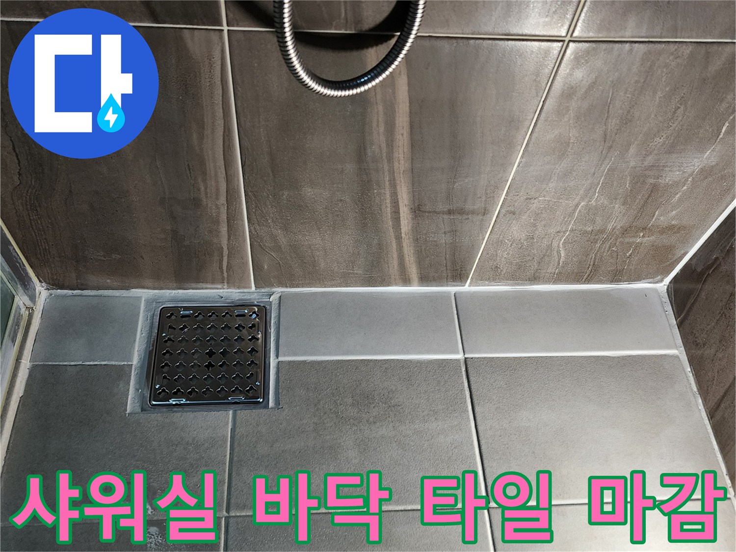 샤워실 바닥의 어두운 톤 타일과 금속 재질의 배수구 덮개 모습 - 방수층 확인 작업
