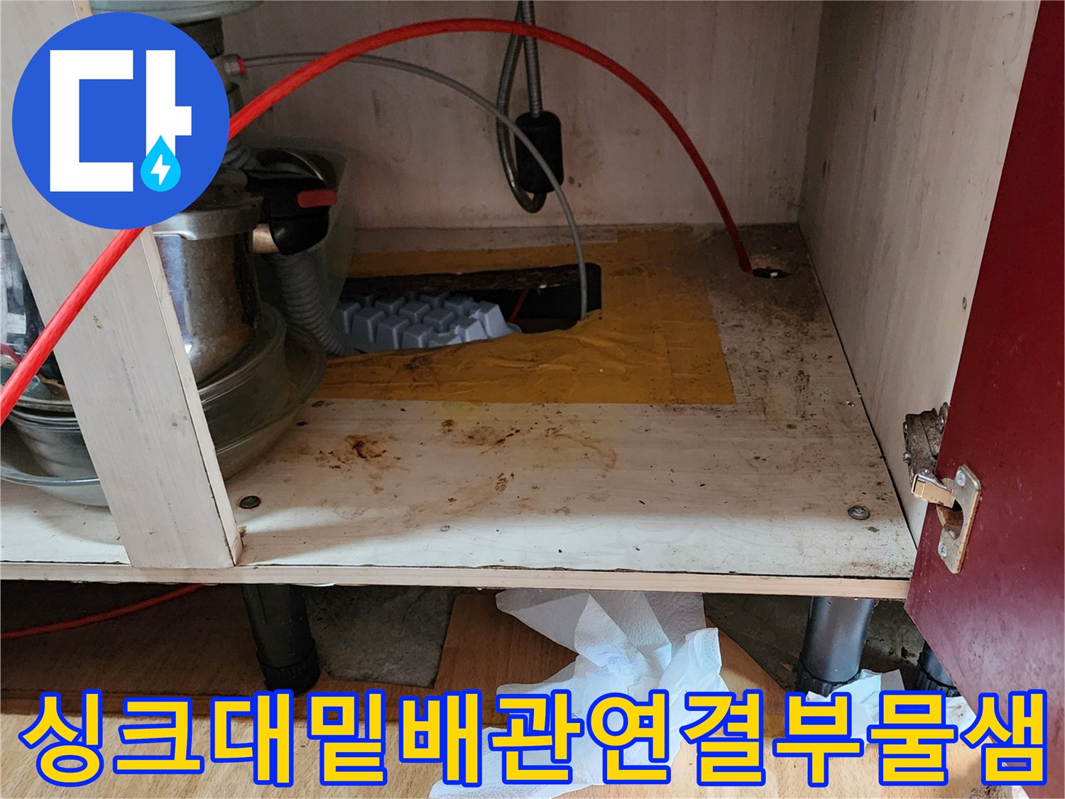 주방 싱크대 하부장 내부의 젖어 있는 배관 연결 부위와 변색된 목재 판넬