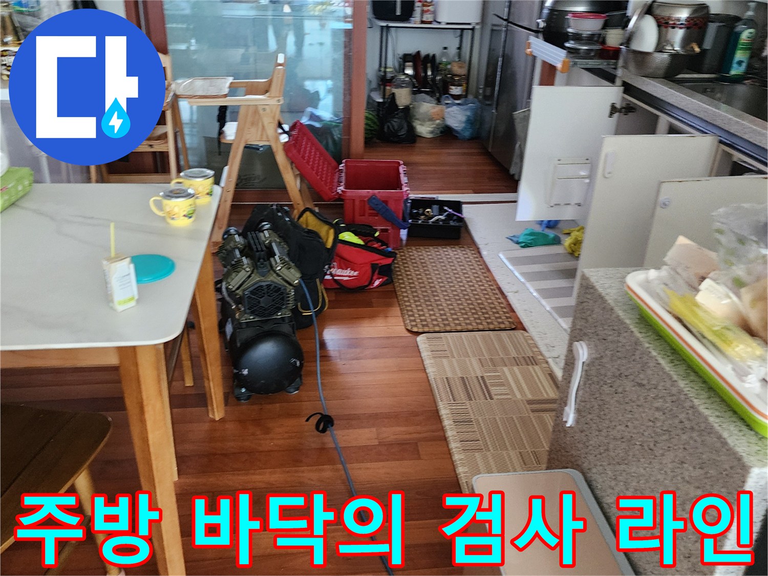 식탁 밑 주방 공간에 배치된 배관 압력 테스트용 장비와 호스