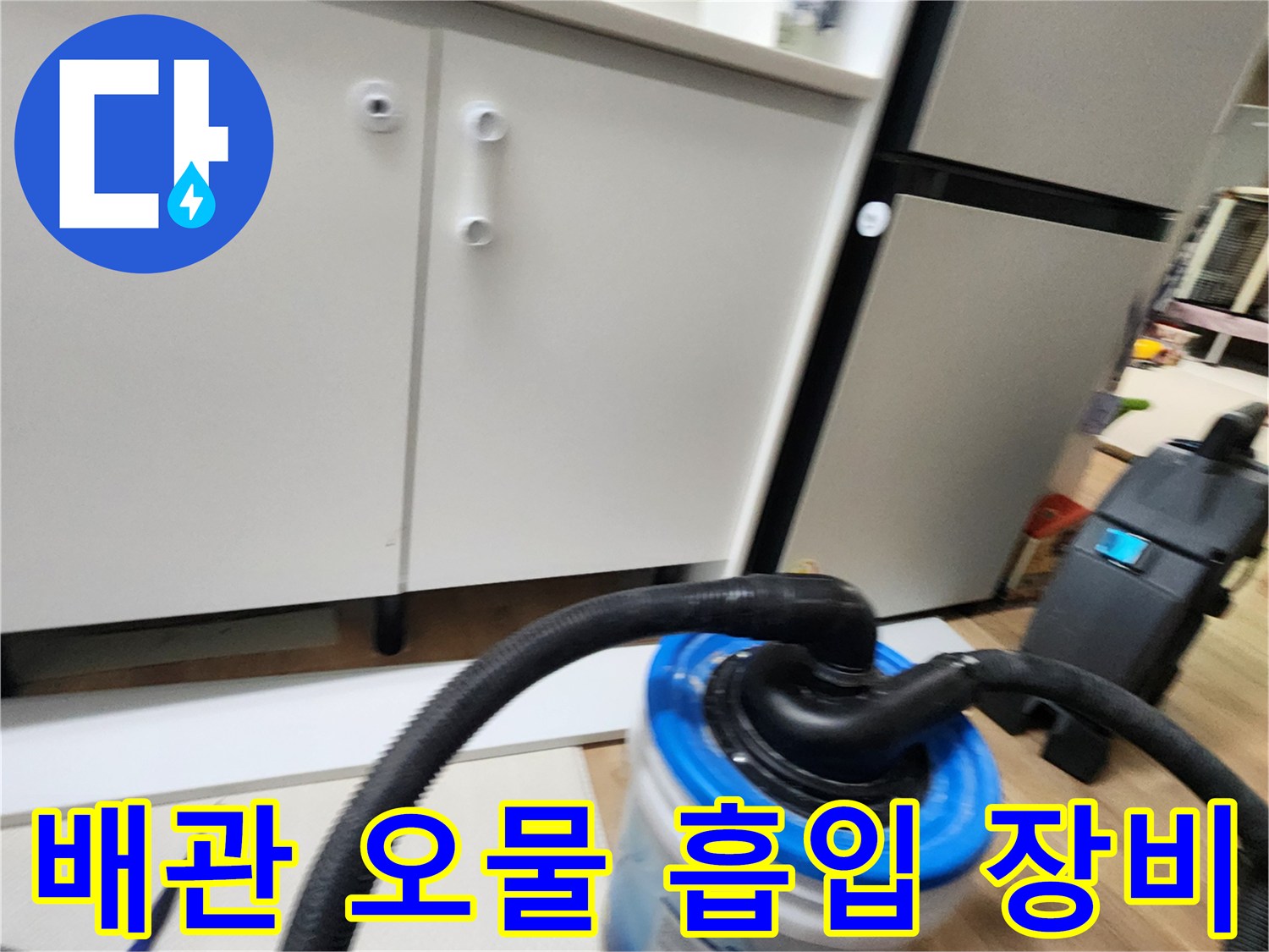 싱크대 하부 배관 청소를 위해 설치된 검은색 호스와 수거용 통