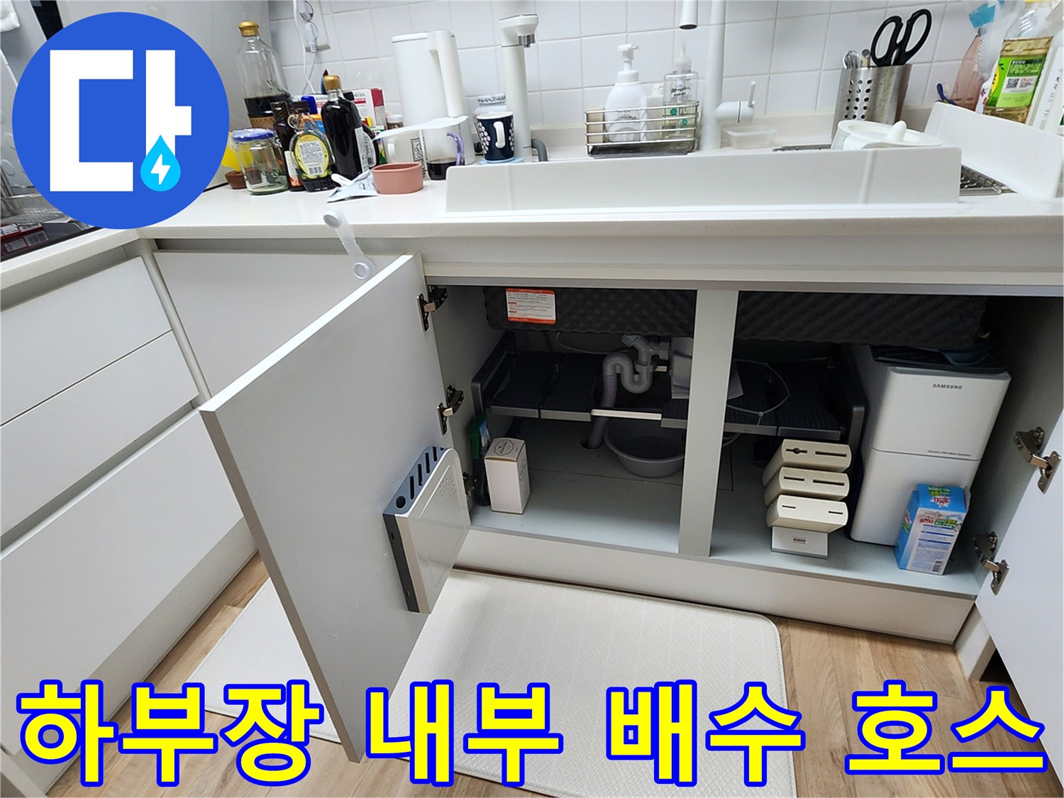 싱크대 하부장 내부에 노출된 배수 호스와 연결 부위 상세 사진