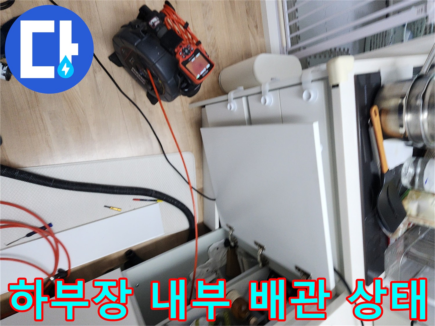 싱크대 하부장 문이 열린 채 배관과 장비가 놓인 현장