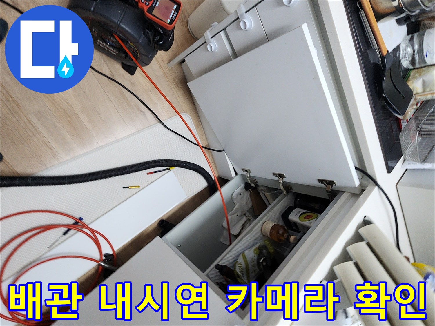 주방 싱크대 아래 배관 내부를 살피기 위해 배치된 내시경 장비와 호스