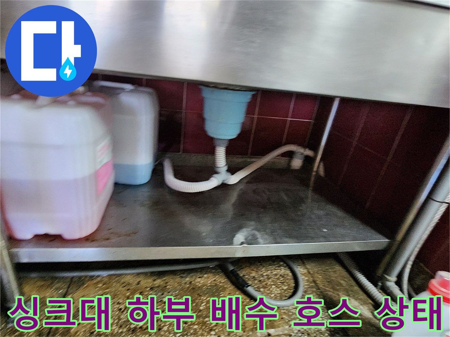 싱크대 아래쪽의 흰색 배수 호스와 파란색 배수통 연결 부위