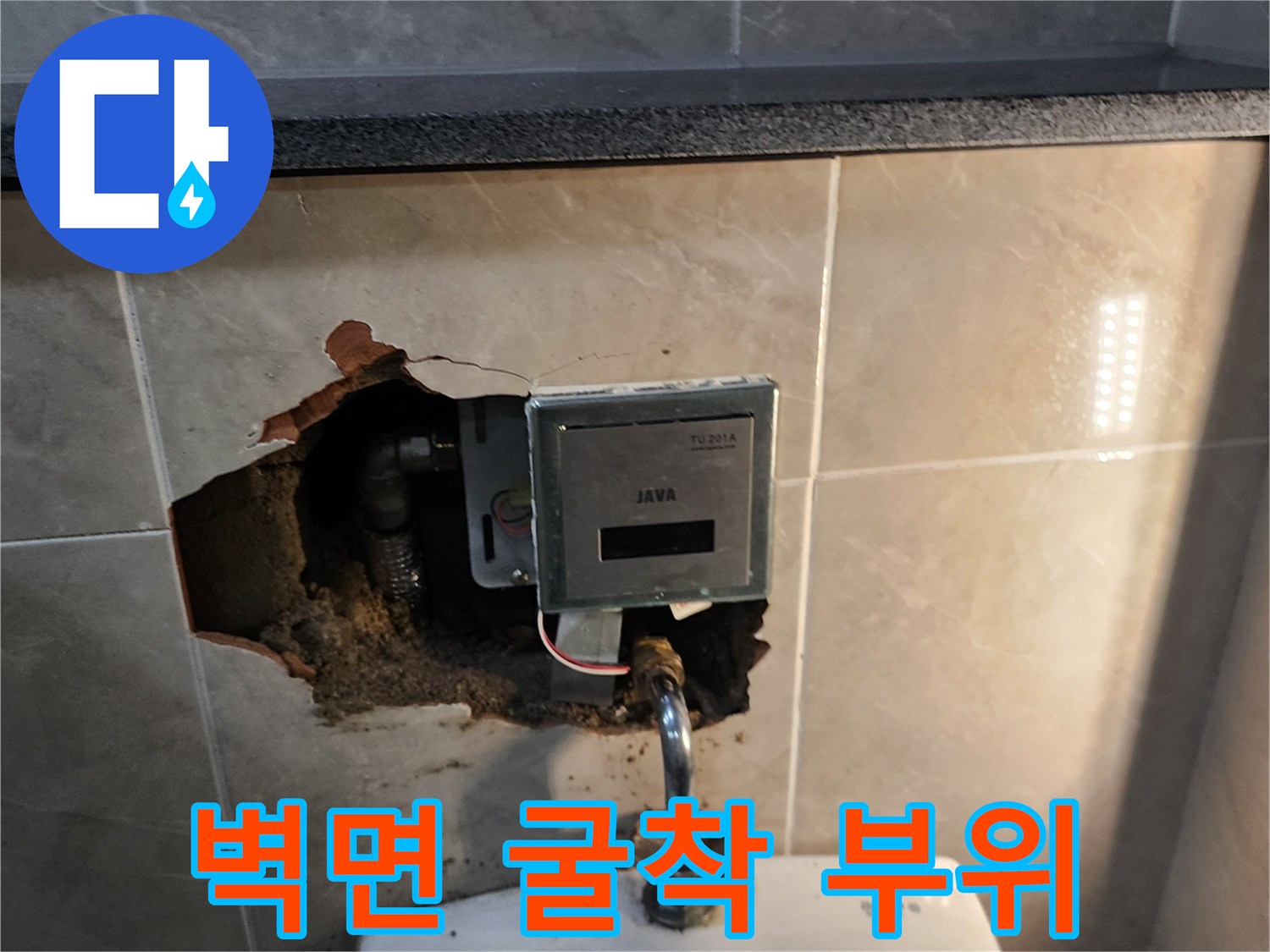 소변기 연결 배관 확인을 위해 벽면 타일을 파손하여 내부를 노출시킨 모습입니다.