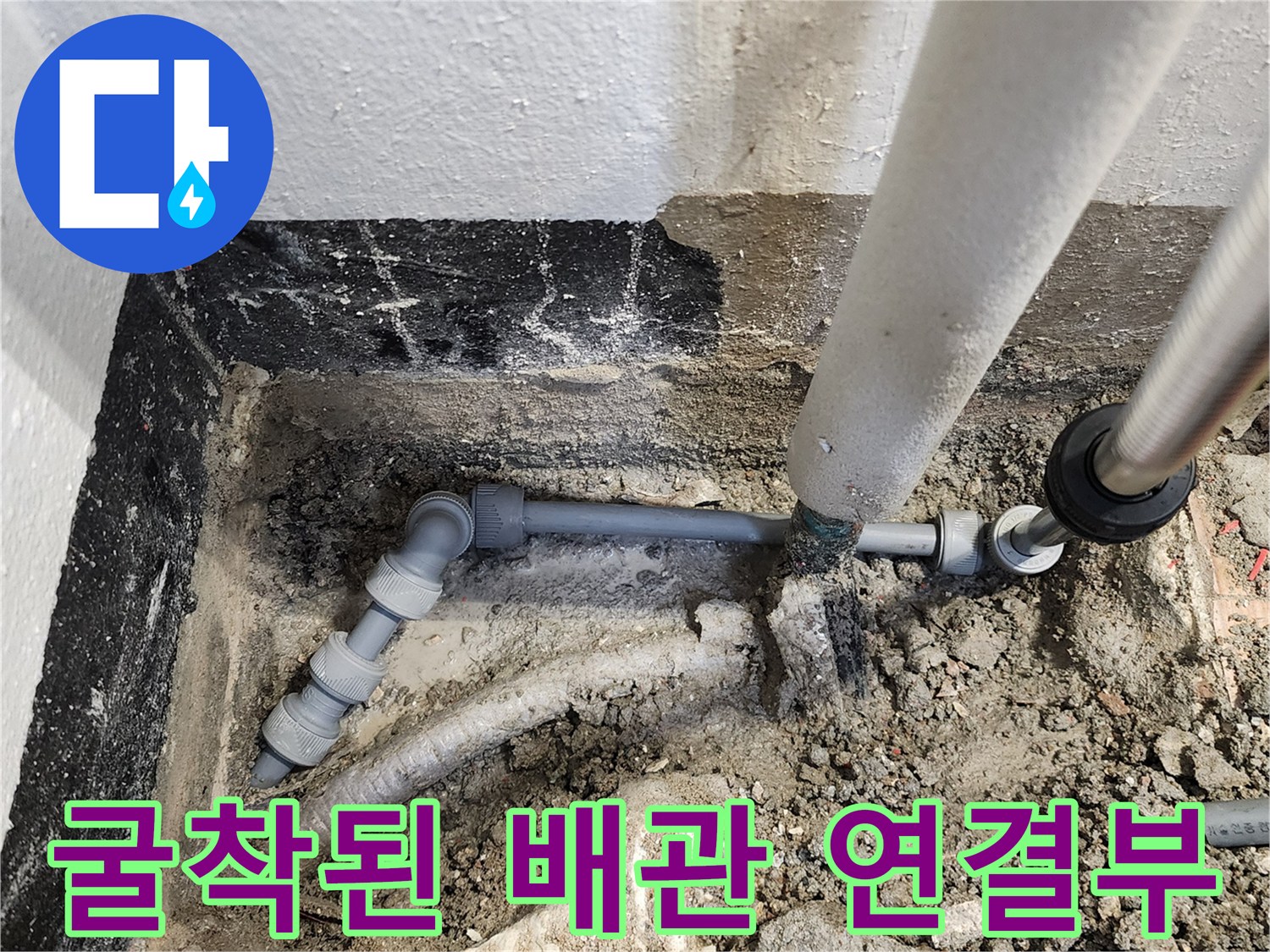 바닥 틈새로 드러난 노후 배관과 흙이 섞인 작업 부위 사진입니다.