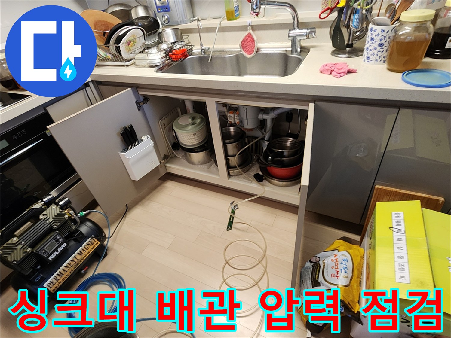 싱크대 하부장 내부의 배수 호스와 공기압 측정 장치