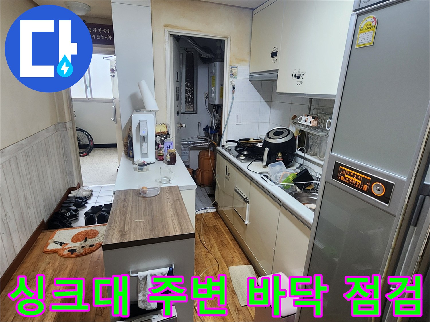 주방 싱크대 하단부와 냉장고 사이 공간의 사진입니다.