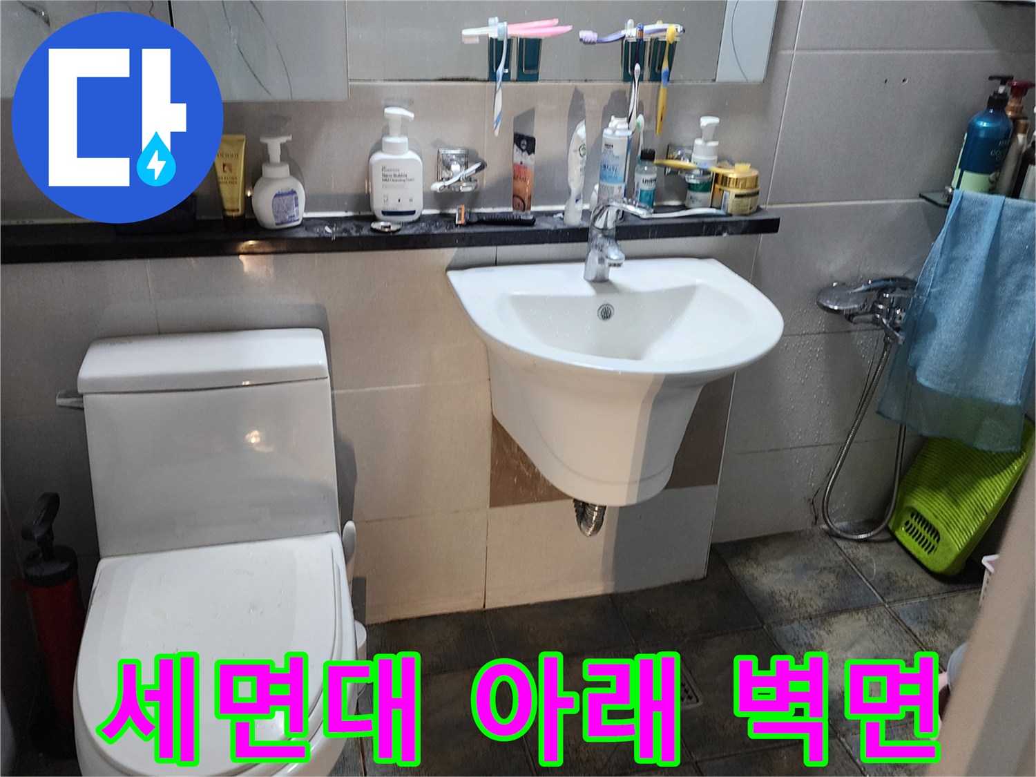 세면대 하단 타일과 변기 옆쪽의 습기 오염 상태를 촬영하였습니다.
