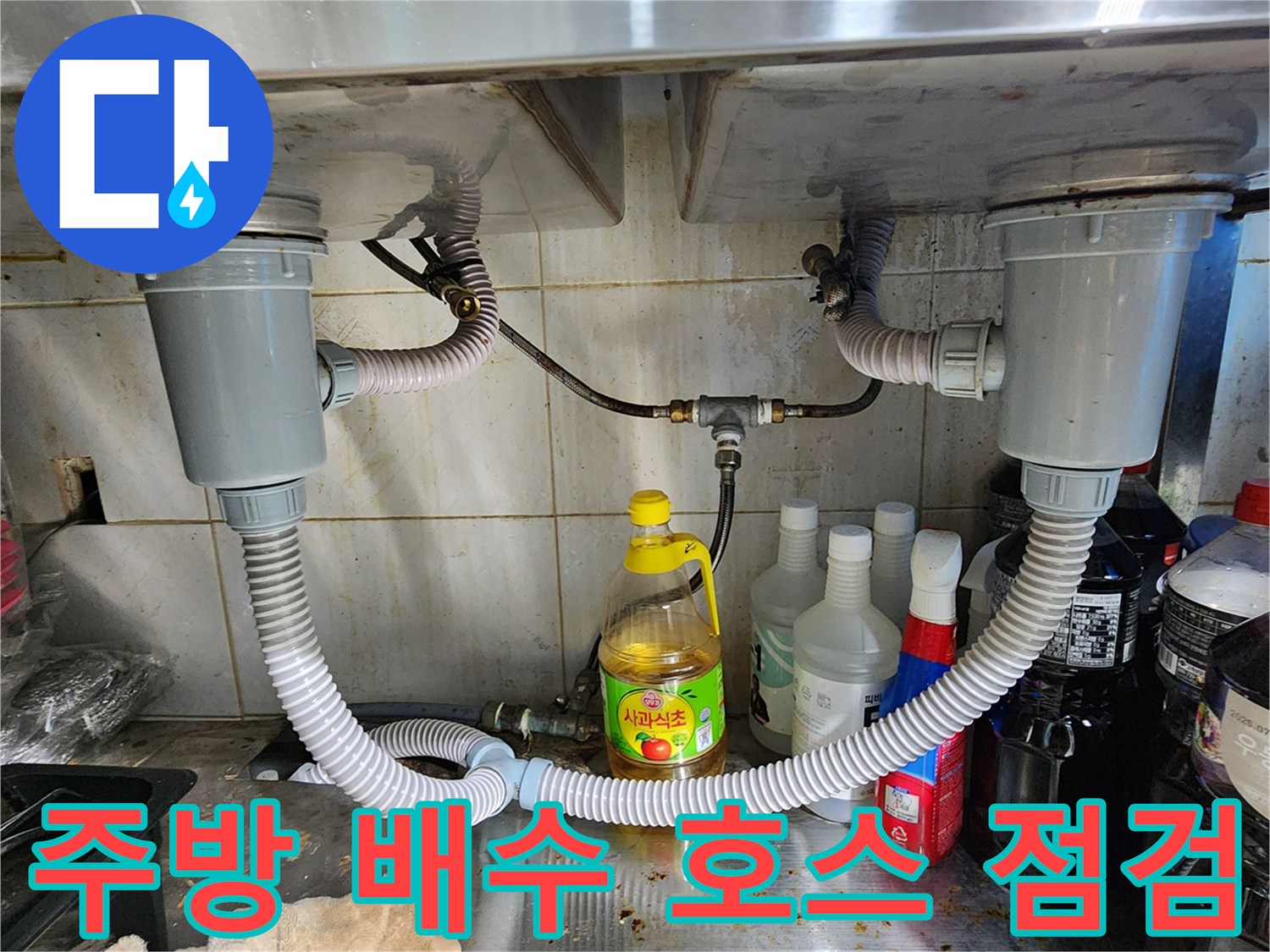 싱크대 하단에 설치된 흰색 주름관 형태의 배수 호스 모습입니다.