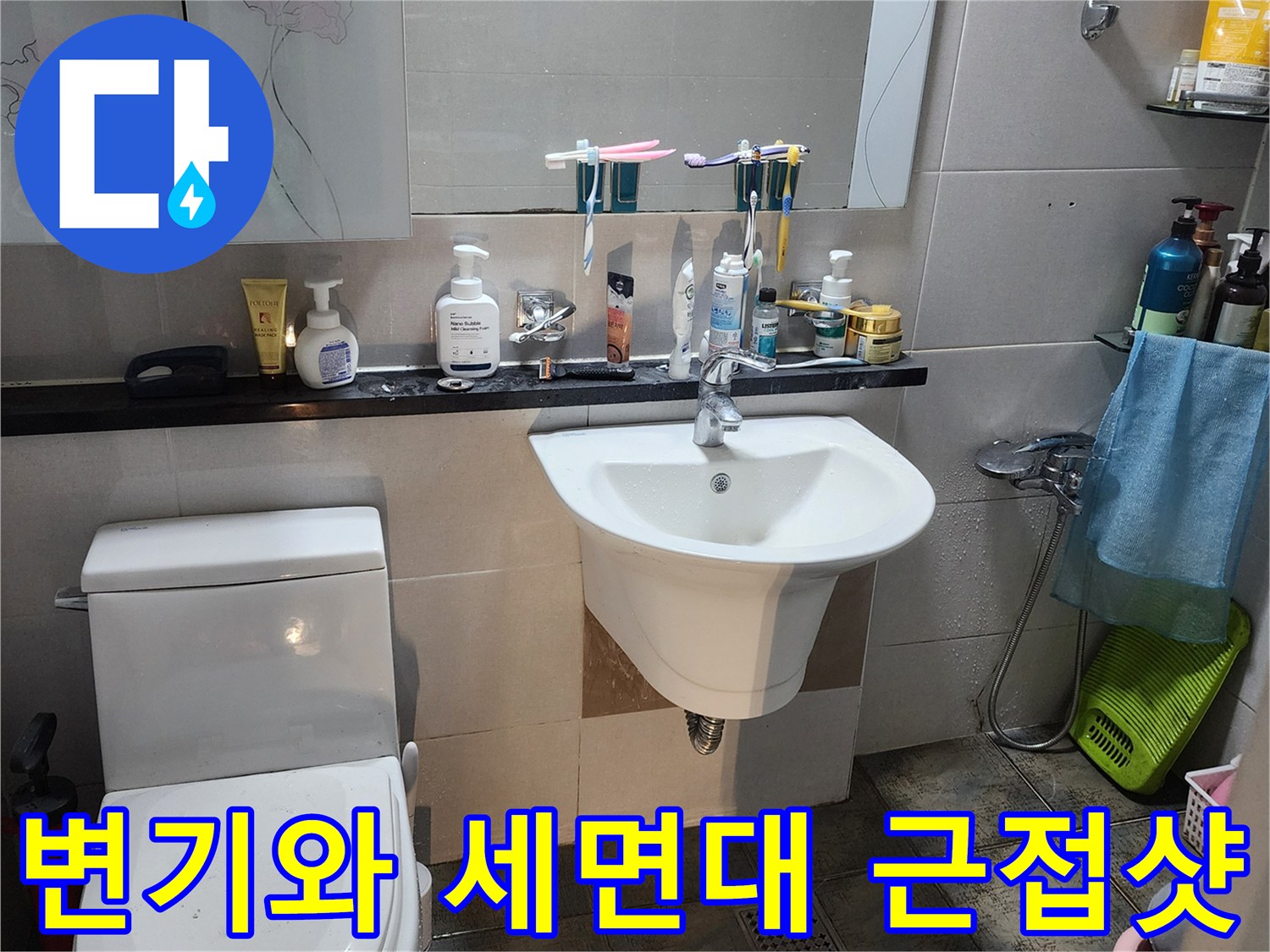 화장실 변기와 하얀색 세면대가 배치된 욕실 내부 모습입니다.