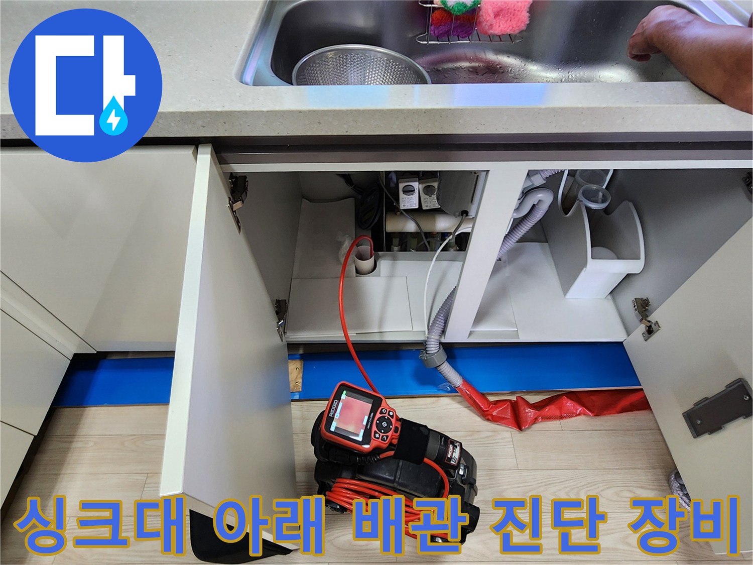 주방 싱크대 하부 배관과 연결된 붉은색 누수 탐지용 공압 장비입니다.