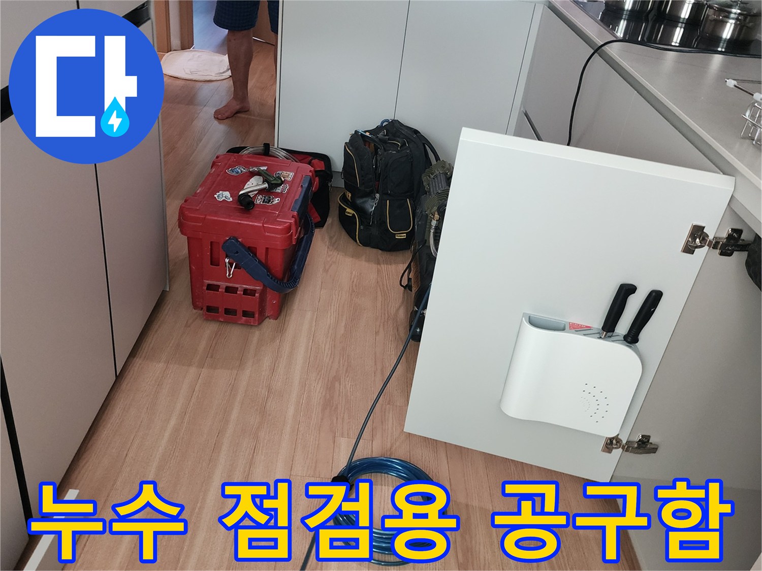 싱크대 아래 작업 공간에 놓인 붉은색 장비함과 연결 호스