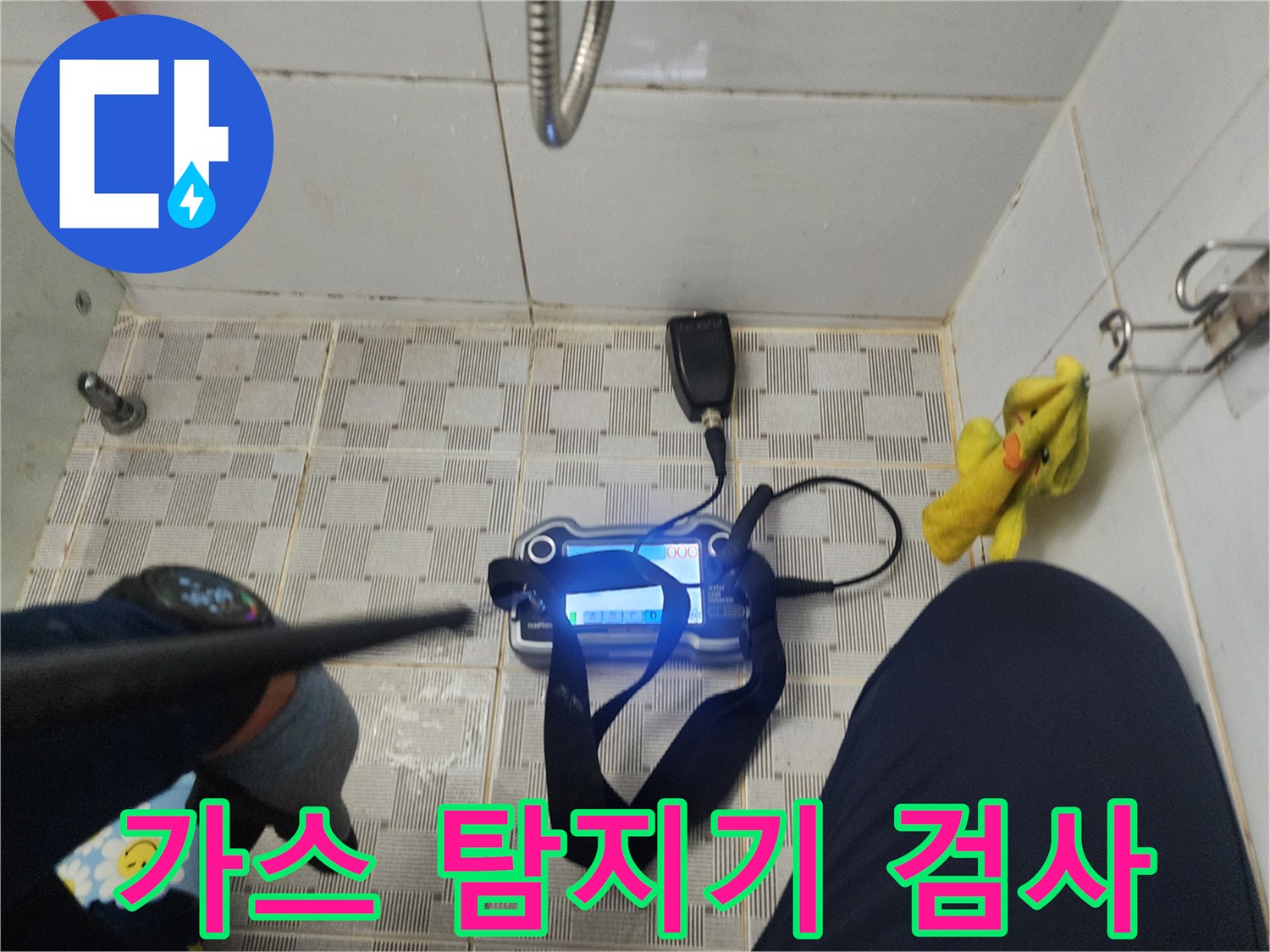 욕실 바닥 타일 위에서-가스 탐지기를 이용한 배관 점검 중인 모습