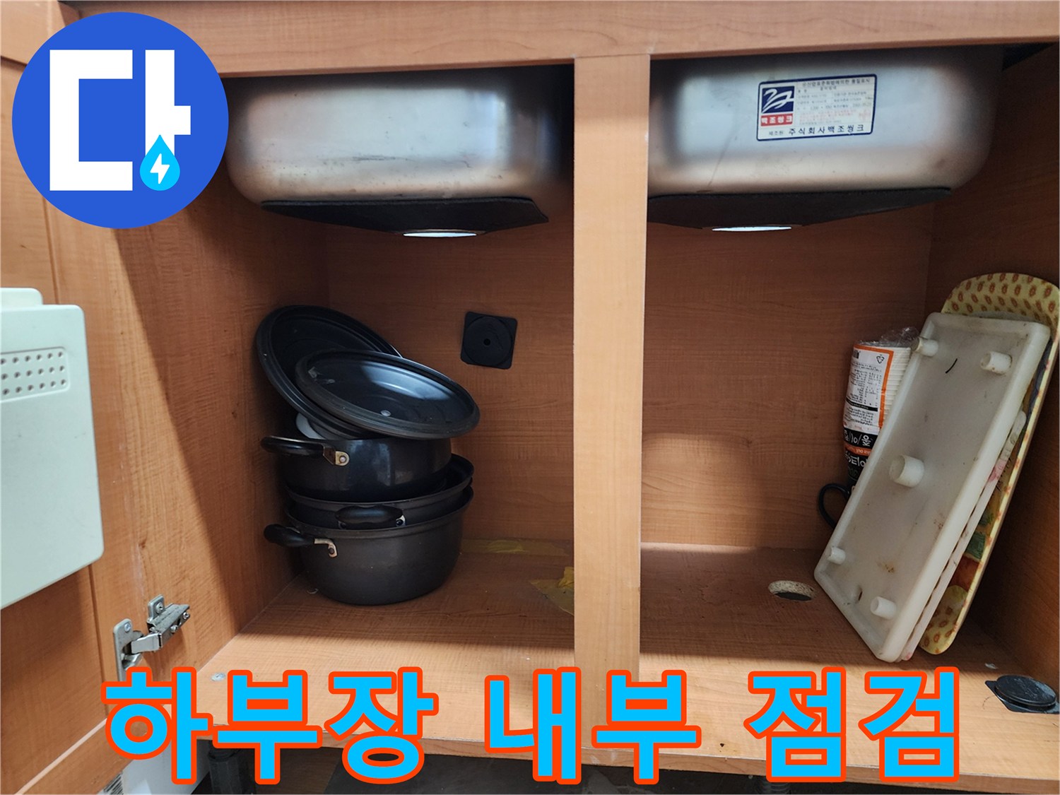 싱크대 하부장 내부 - 누수 부위를 찾기 위해 꼼꼼하게 살펴보고 있습니다.
