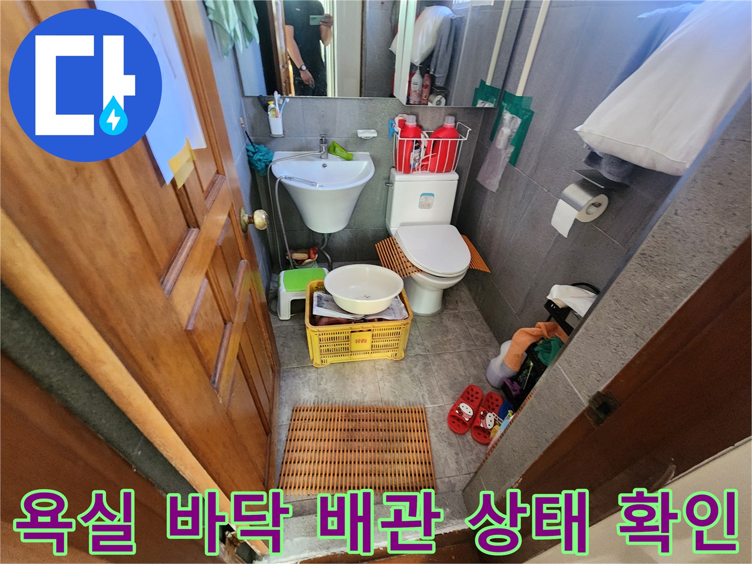 변기와 세면대 주변의 타일 바닥 및 배관 연결부를 촬영한 사진