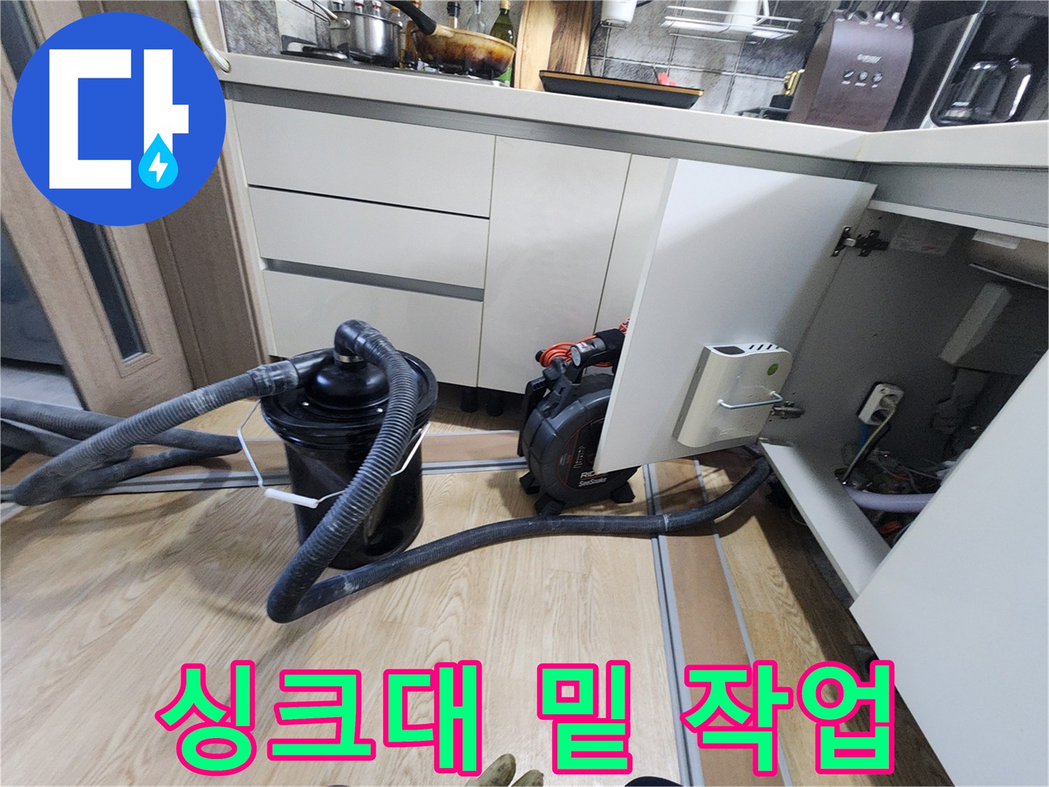 싱크대 아래쪽 배관 상태를 살피기 위해 준비된 청소 장비와 호스입니다.