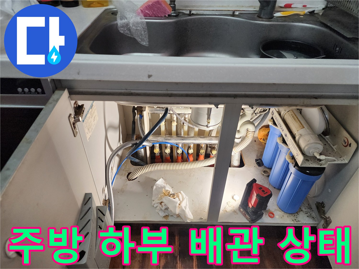 정수기 필터와 다양한 호스가 연결된 싱크대 하부장 내부의 배관 구조