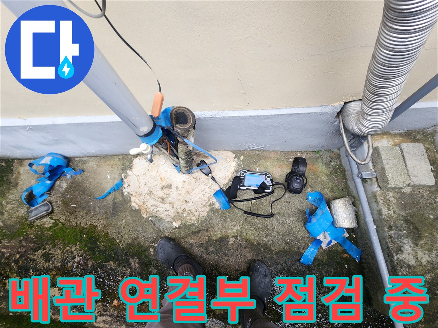 건물 외벽 배관 주변의 젖은 땅과 누수 측정 장비 배치