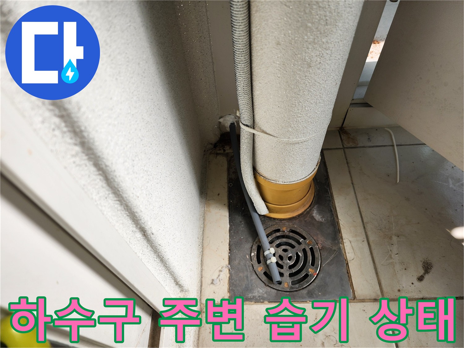 베란다 배수구 드레인 주위의 젖은 타일과 노출된 배관 사진입니다.