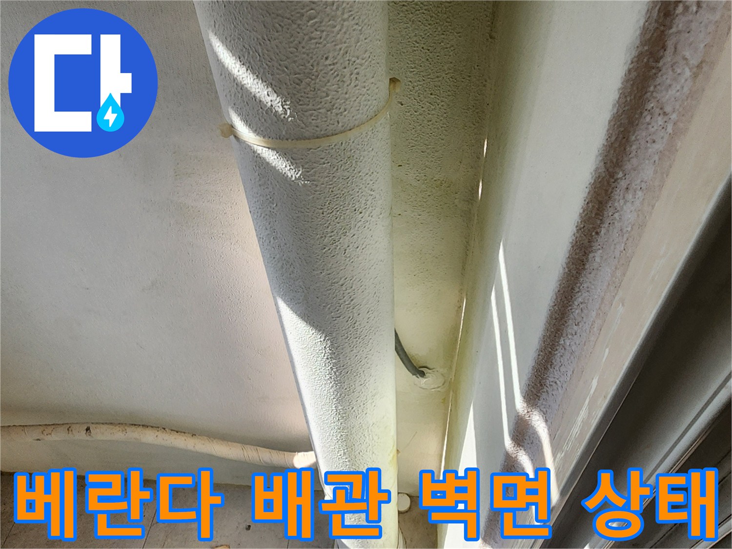 베란다 외벽에 설치된 흰색 배관과 주변 벽면의 습기 상태를 보여주는 사진입니다.