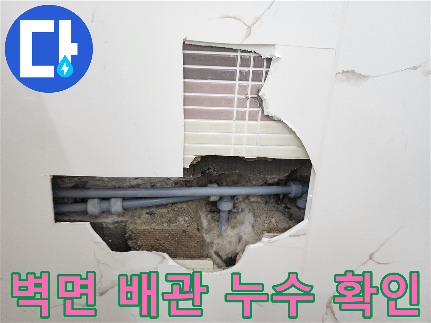 화장실 벽면 타일을 제거하여 노출된 회색 배관 연결 부위의 상태를 보여주는 사진입니다.