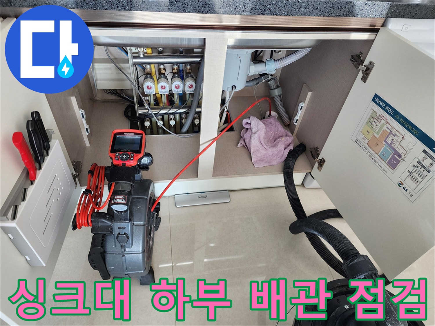 주방 싱크대 아래쪽 배수관과 석션 장비가 놓인 작업 현장 모습입니다.