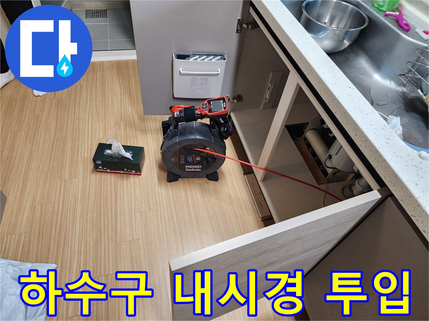 싱크대 하부 배관의 막힘 정도를 파악하기 위해 내시경 카메라를 배관 안으로 삽입하는 장면