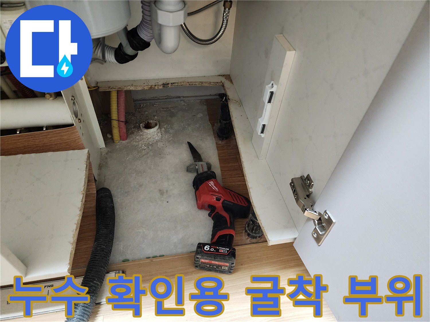 싱크대 하부 바닥의 젖은 부분과 노출된 배관 - 누수 원인 조사 중