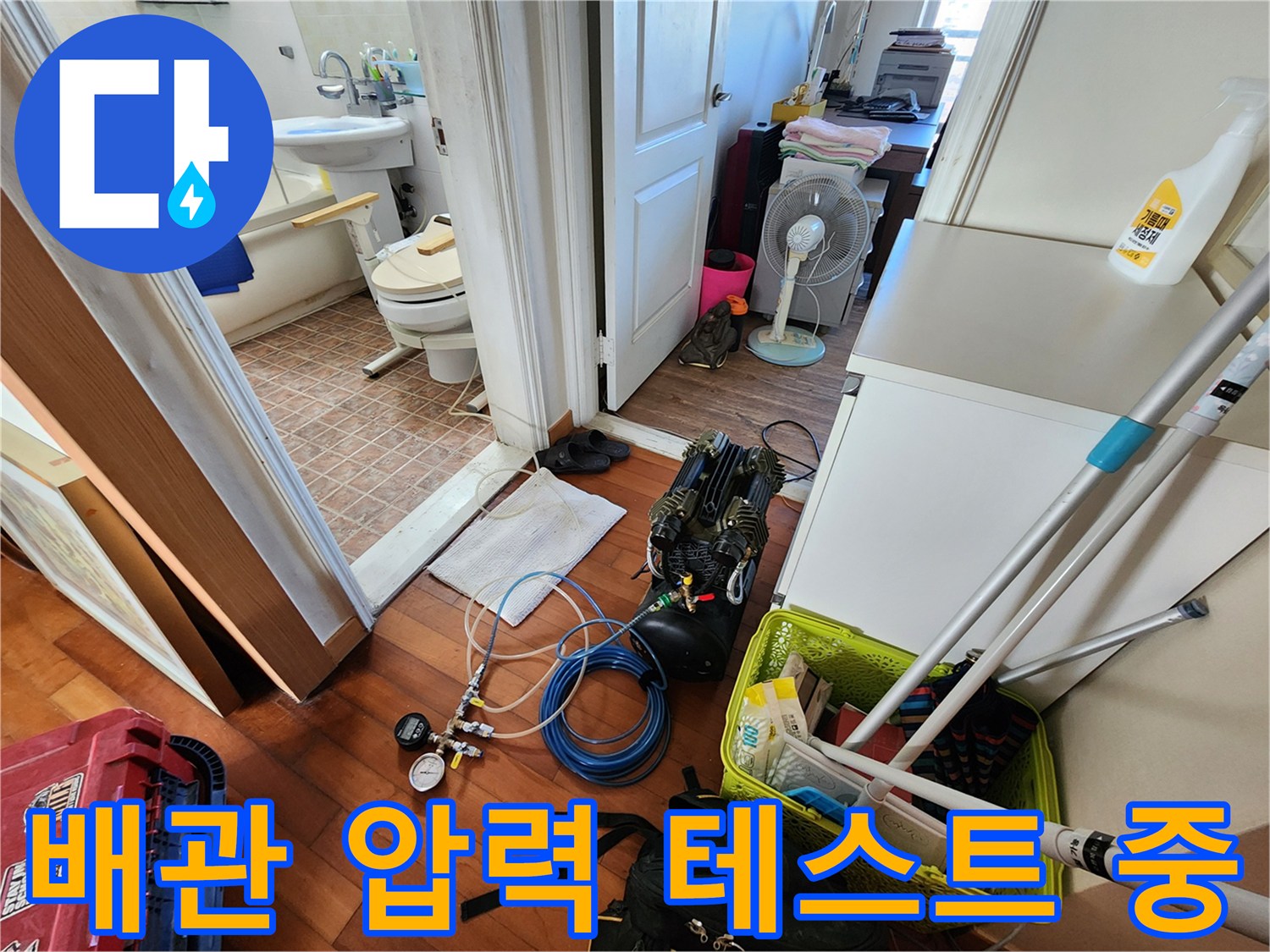 욕실 입구 바닥에 놓인 배관 공압 테스트 장비와 게이지