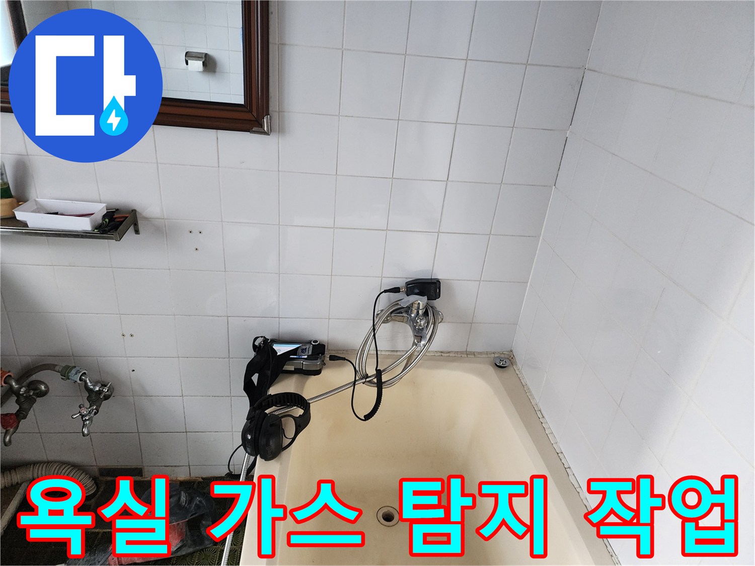 벽면 타일 사이에 연결된 배관 누수 탐지용 호스와 장비입니다.