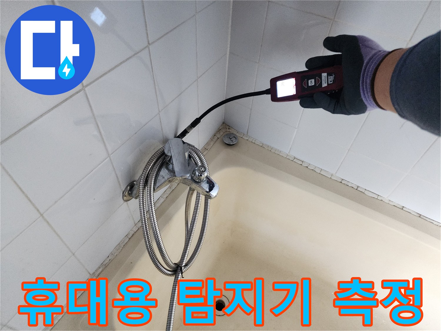 욕조 하부 타일 부위-배관 누출 반응을 확인하기 위해 탐지기를 사용하여 검사하는 장면