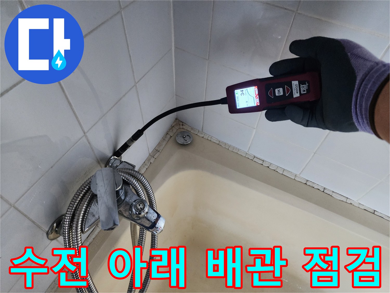 탐지 장비의 측정 센서를 욕조 옆 타일 벽면에 대고 있는 사진입니다.