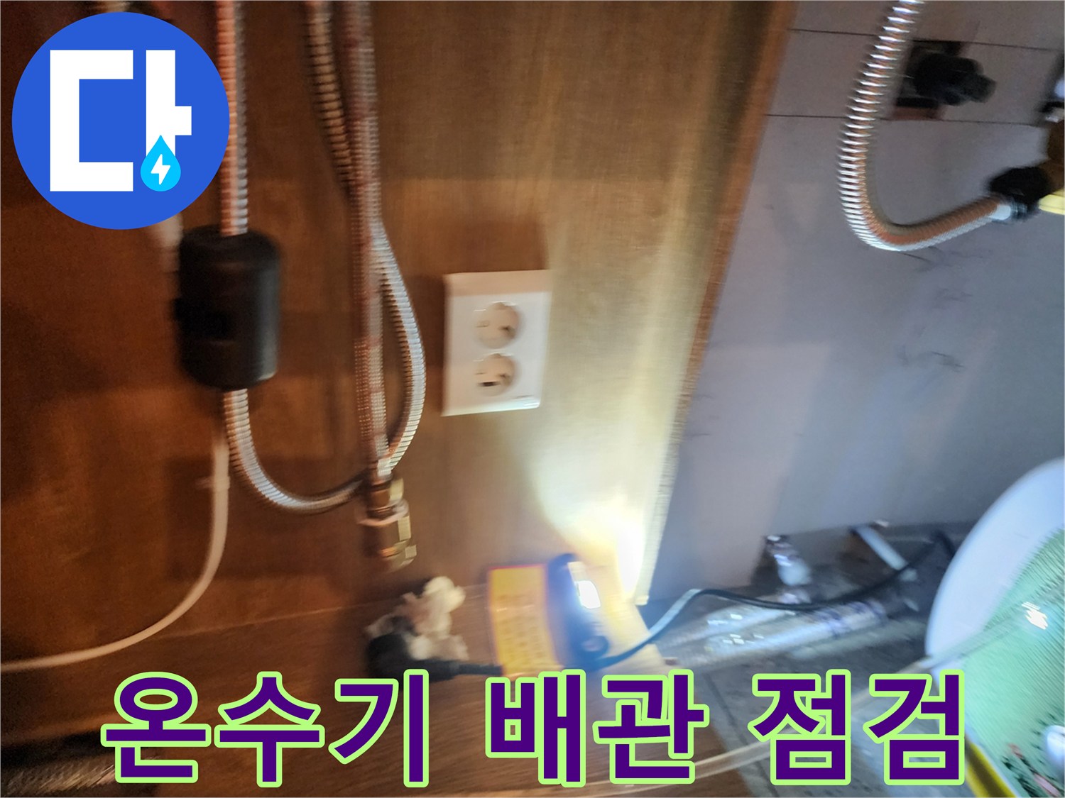 전기 온수기 하단에 연결된 플렉시블 호스와 주변 배관의 상태를 보여주는 사진입니다.