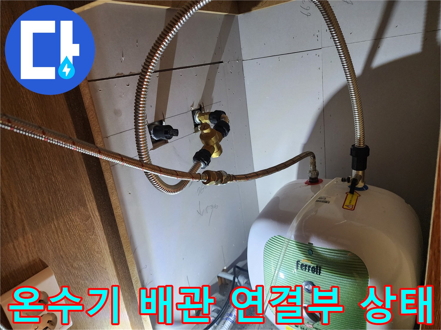 주방 하부장 내부-전기 온수기와 연결된 금속 호스 접합 부위 사진