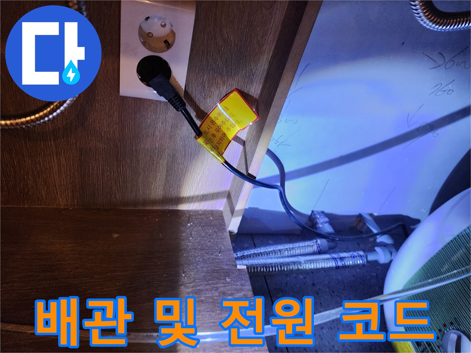 주방 하부장 내부의 전기 콘센트와 온수기 연결 배관 모습-누수 확인 과정