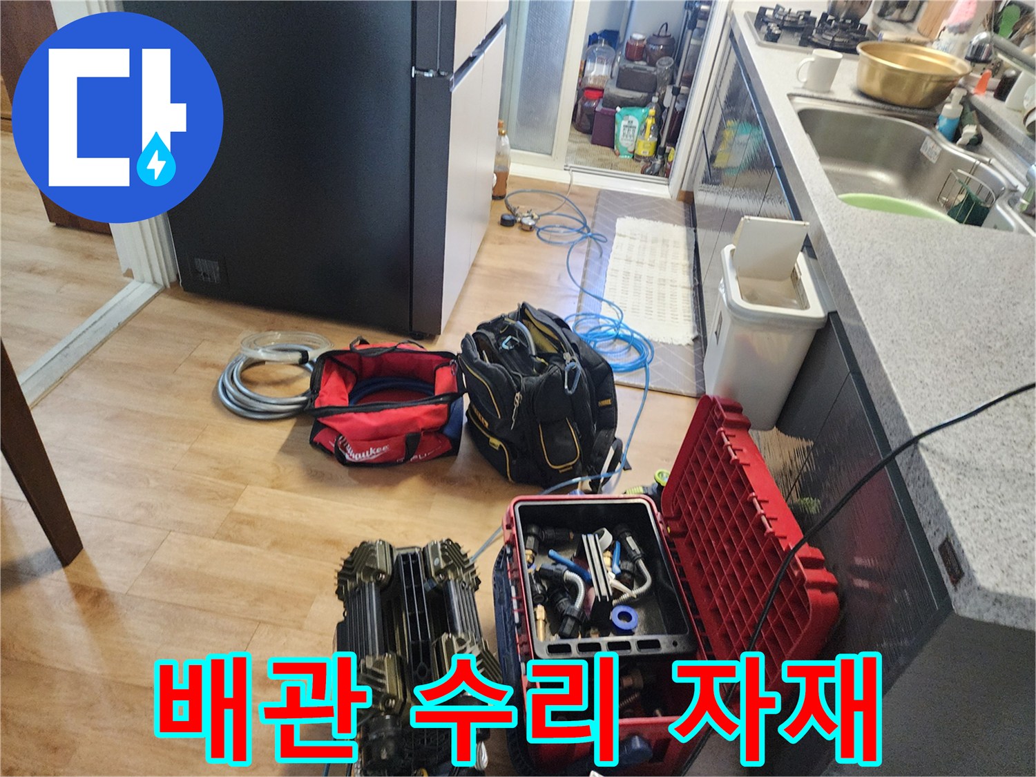 작업 현장 바닥에 놓인 다양한 배관 연결 부속과 공구함