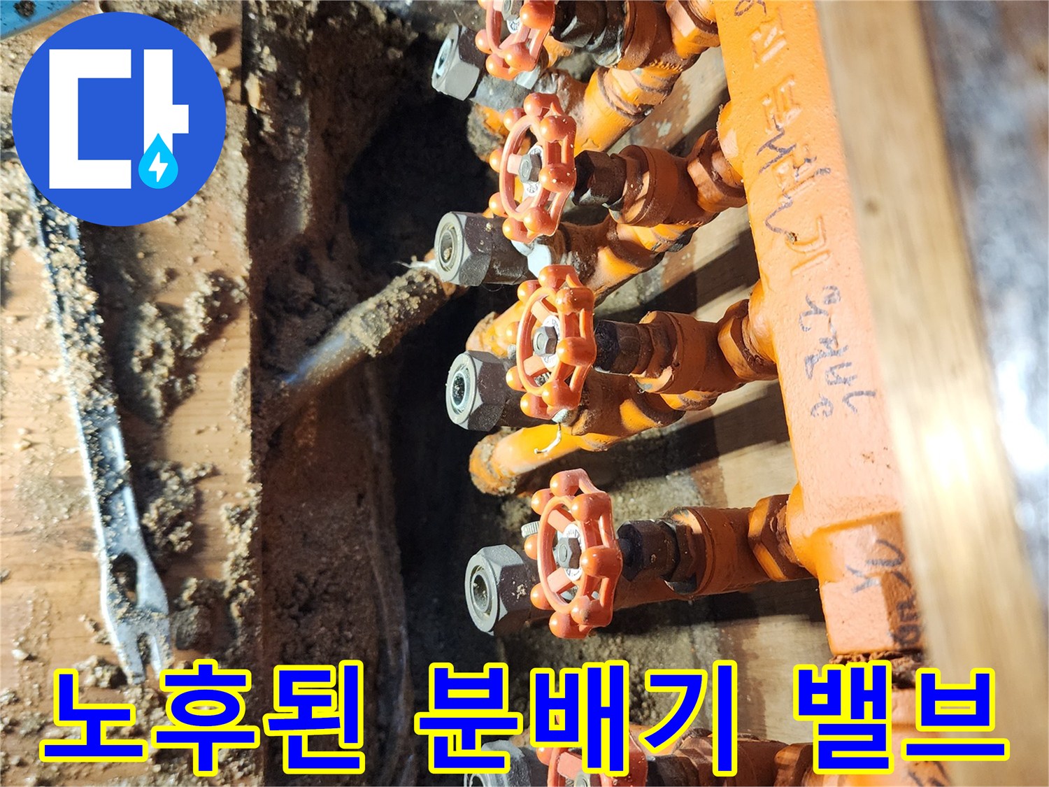 오렌지색 보온재가 씌워진 노후 배관 및 분배기 사진입니다.