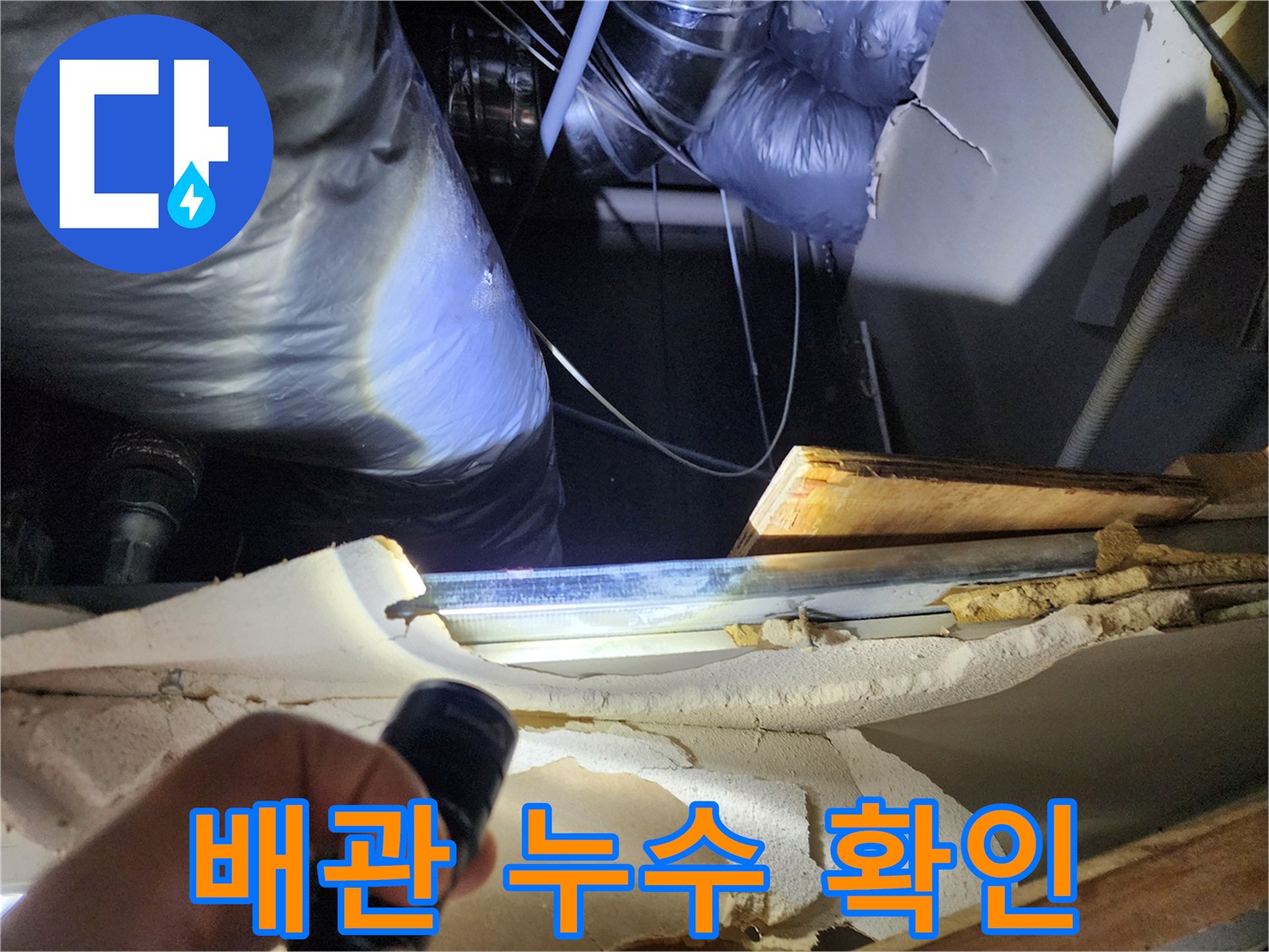 손전등 조명으로 싱크대 아래 배관의 균열 여부를 조사함