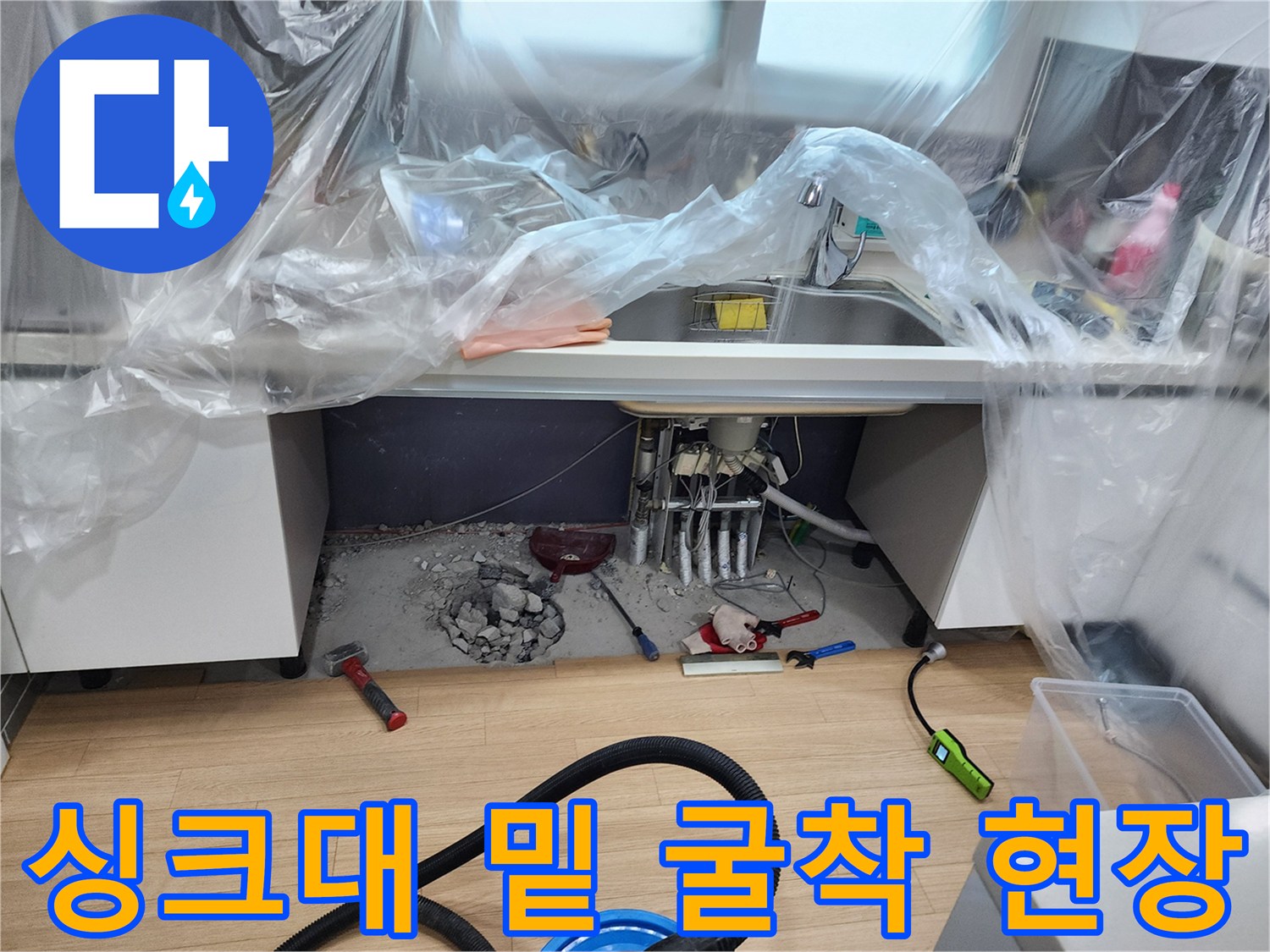 싱크대 아래 바닥을 파내어 노출된 배관과 주변 자재들