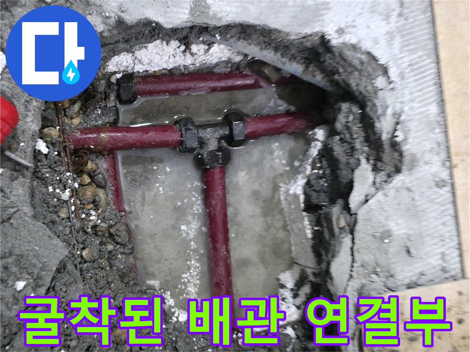콘크리트 층을 파내어 노출시킨 붉은색 배관의 수리 전 상태입니다.